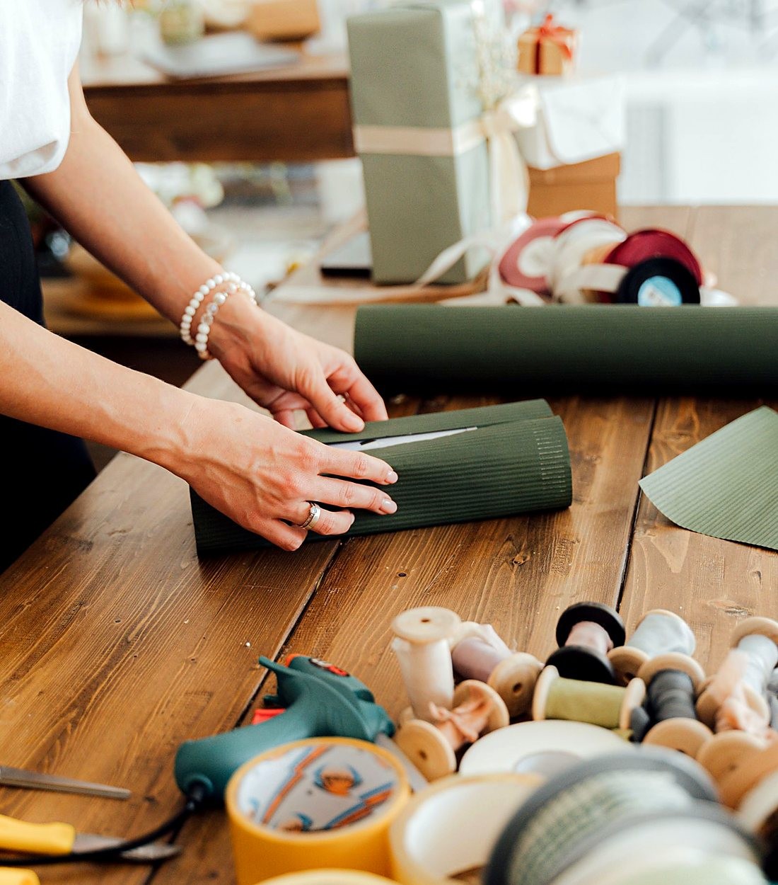 Mesa de trabalho com embalagens, fitas e brindes sendo preparados
